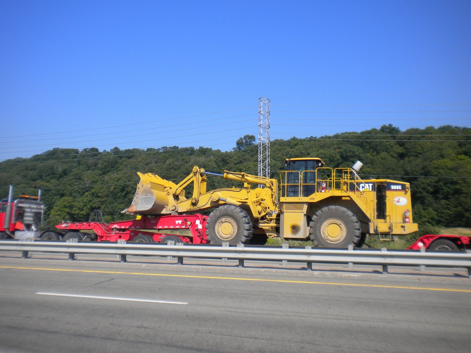 Chargeuse Caterpillar transportée sur fardier en bordure d'autoroute