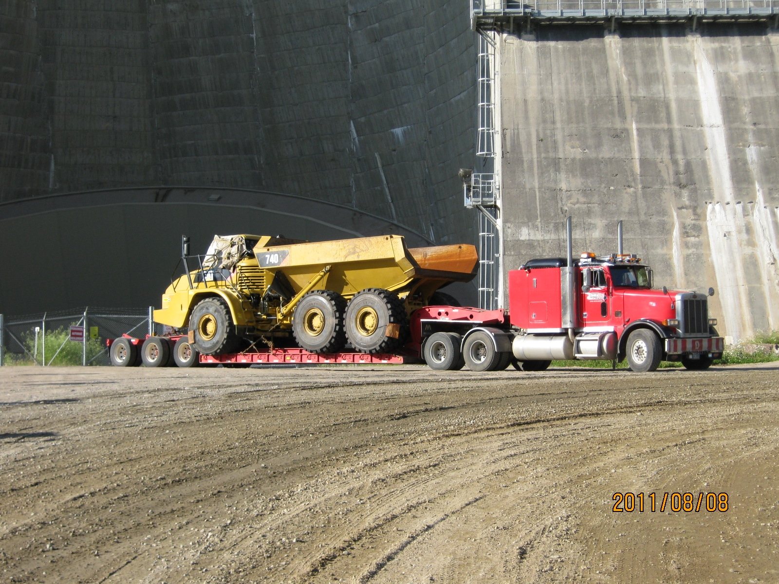 Tombereau articulé transporté sur fardier en chantier